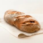 Pão em forma de cacete comprido em cima de um pano dobrado