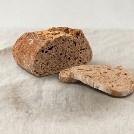 Pão escuro cortado com duas fatias ao lado em cima de uma toalha de pano branca