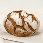 Pão de forma redonda com aspeto rústico em cima de um pano branco