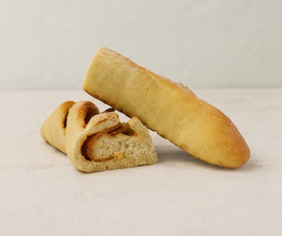 Duas metades cortadas de pão com chouriço numa toalha de pano